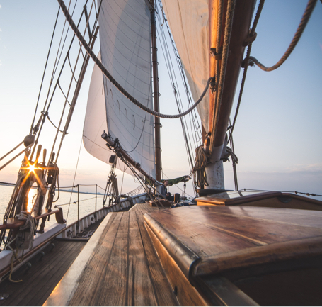 A view of sails from the deck of a large wooden ship.