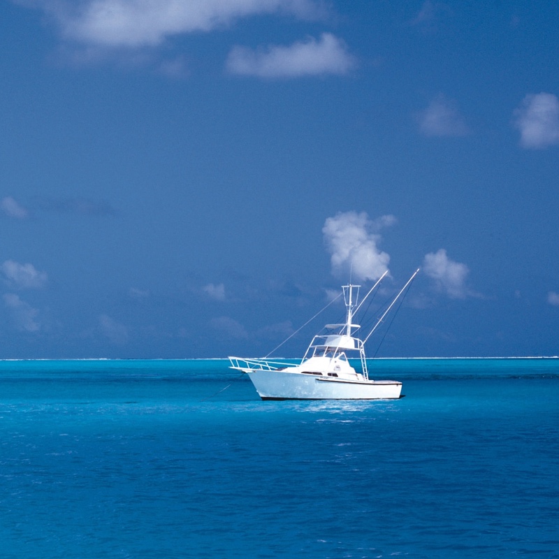 A boat on the ocean with blue skies in the background.